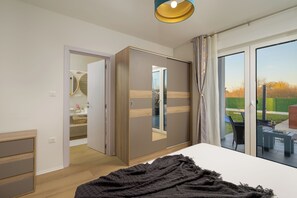 Une chambre à coucher comprenant un lit, une armoire, un miroir et une porte-fenêtre coulissante donnant sur un patio extérieur.