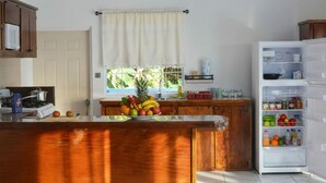 Una cocina con una isla de madera, un refrigerador blanco y un ventanal con cortina.