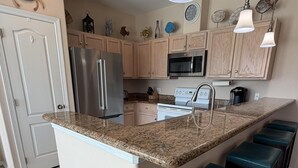 A kitchen with a central island, stainless steel appliances, wooden cabinets, and bar stools. - A cozy, family‑friendly 31TP (Gail)