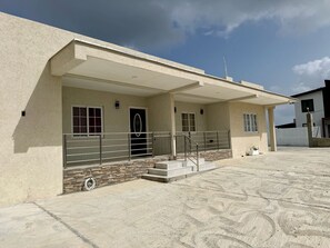 A building with a covered entrance, a stone facade, and a metal railing. - Careffe Gardens Stunning Breezy 2-bedroom Hilltop Villa 2 (Gros Islet)