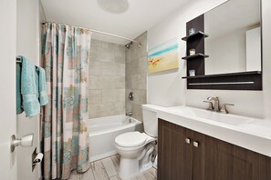 A bathroom with a bathtub, toilet, and a sink with a mirror above it. - 2BR Atlantis Oceanfront Condo, Outdoor Pool (Ocean City)
