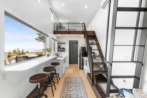 Une cuisine compacte avec un coin bar, un escalier et une vue sur l’extérieur.