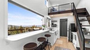 Een moderne keuken met een bar, een trap en uitzicht op de omgeving.