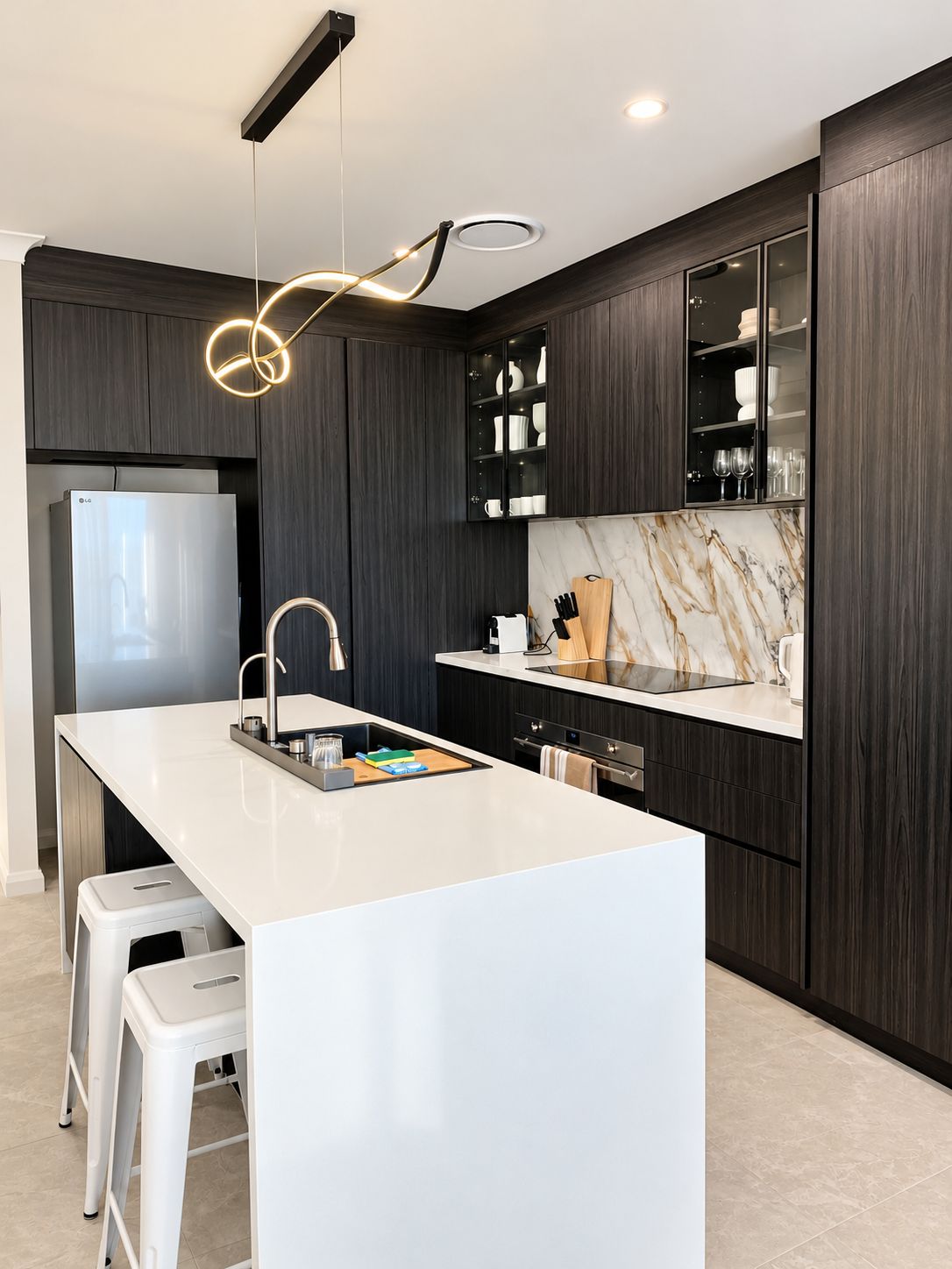 Une cuisine moderne avec des meubles en bois foncé, un îlot central blanc et un pare-feu en marbre.