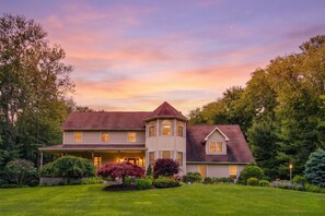 A two-story house with a wrap-around porch, a tower section, and a well-maintained lawn.