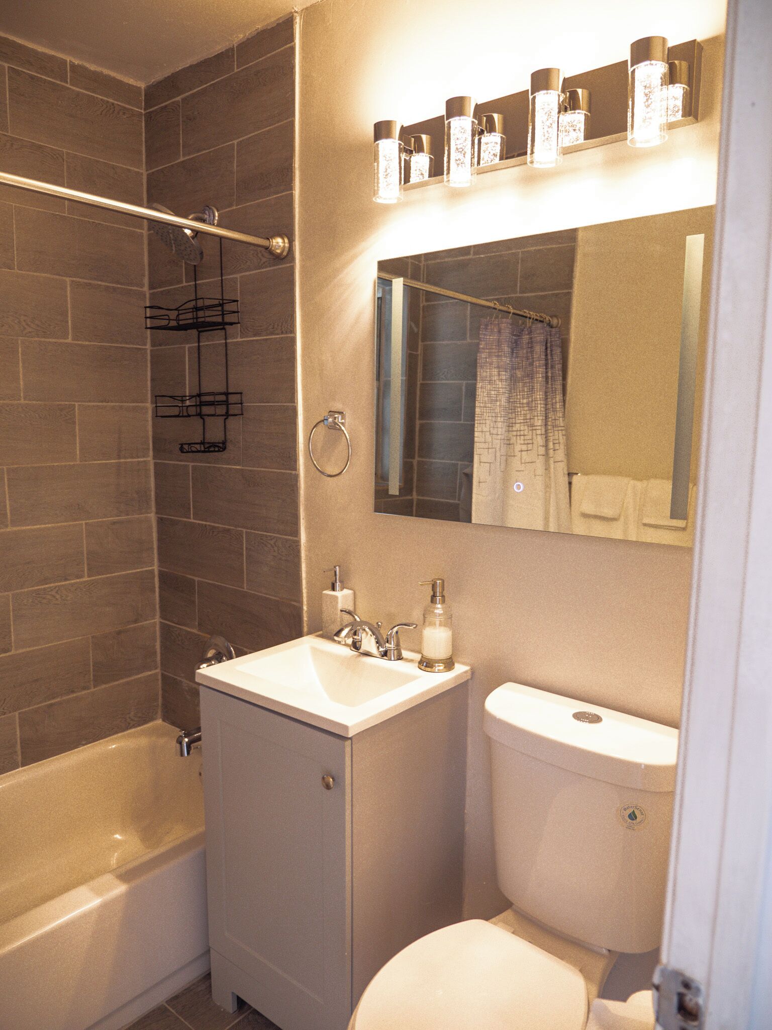 A bathroom with a bathtub, a sink, a toilet, and a mirror.