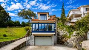 A two-story house with a garage, a stone retaining wall, and a grassy yard. - House near Barro Beach Llanes | El Sumidoriu (Barro (Llanes))