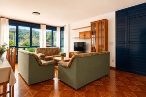 Uma sala de estar com um sofá, uma televisão e um armário.