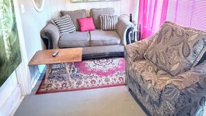 Un salon comprenant un canapé, un fauteuil à motifs, une table basse, un tapis et un grand tableau abstrait accroché au mur.
