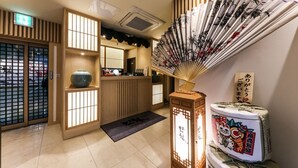Un interior japonés tradicional con puertas correderas, un mostrador de recepción y un abanico decorativo.