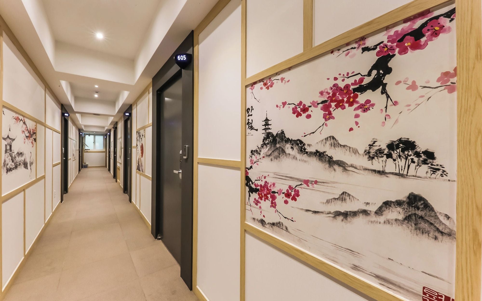 A hotel corridor with doors numbered 605 and 606, featuring traditional artwork on the walls.