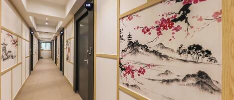 A hotel corridor with doors numbered 605 and 606, featuring traditional artwork on the walls.