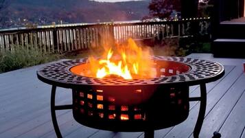 A fire pit on a wooden deck with a view of the hills.