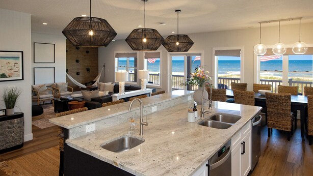 Een moderne keuken met een groot eiland, twee spoelbakken en uitzicht op zee.