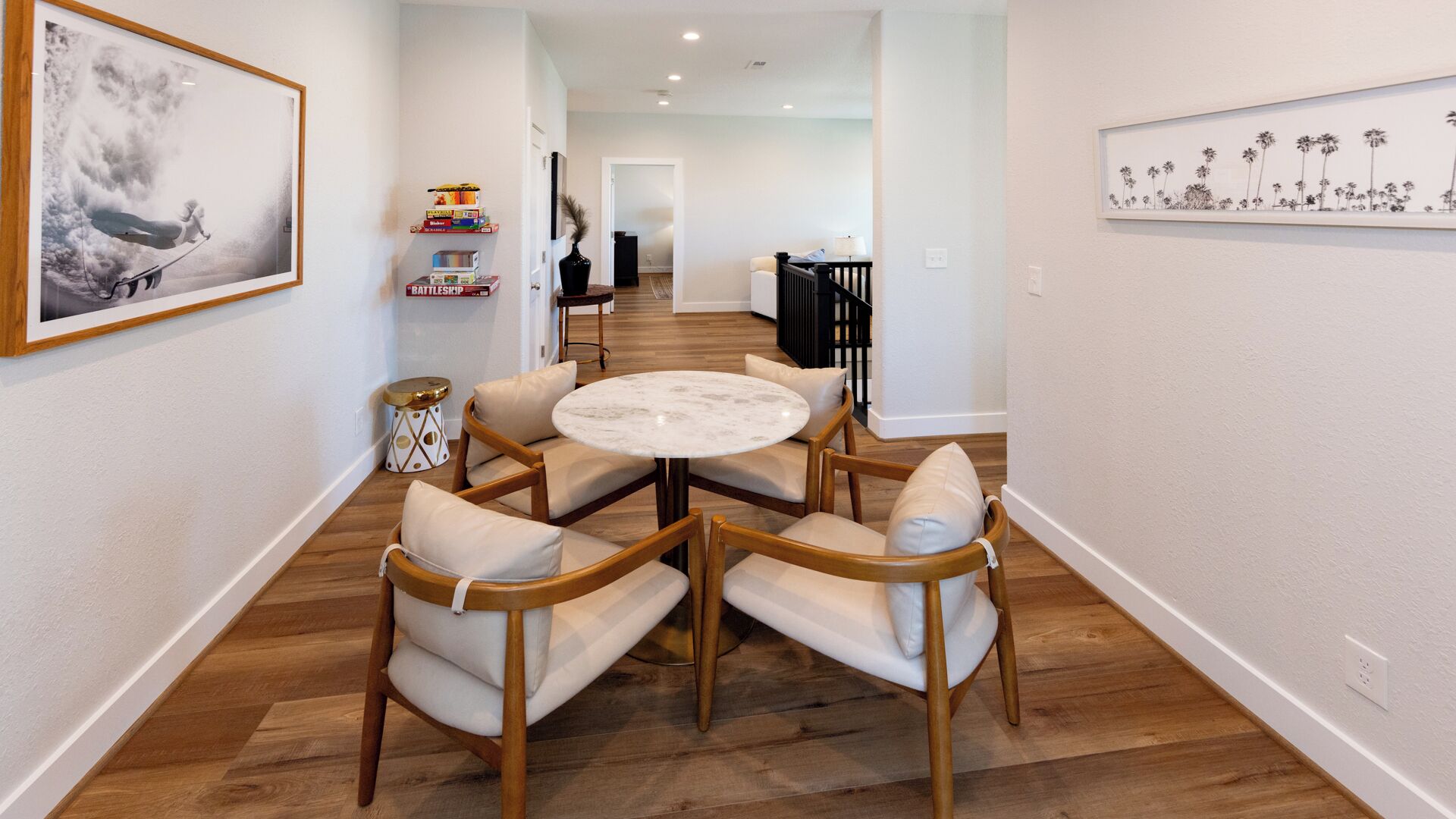 A dining area with a round table and four chairs, a bookshelf with books, and a framed picture on the wall.