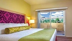 Una habitación de hotel con cama, ventana, balcón y una silla.