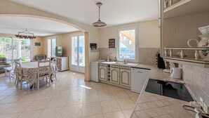 Une cuisine spacieuse avec un coin repas, de grandes fenêtres et une vue sur l’extérieur.