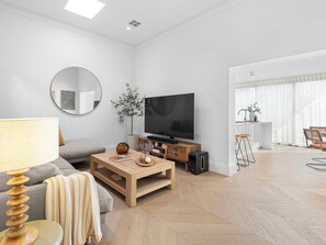 A modern living room with a flat-screen TV, a round mirror, a wooden coffee table, and a sofa.