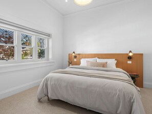 A bedroom with a bed, a window with a view, a bedside table with a lamp, and a nightstand with a lamp.