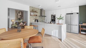 Een moderne keuken met witte kasten, een centraal eiland en een eetgedeelte met houten stoelen en een tafel.