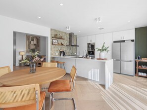 A modern kitchen with white cabinets, a central island, and a dining area with wooden chairs and a table.