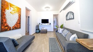 A modern living room with two sofas, a coffee table, a TV, and a heart-shaped artwork on the wall.