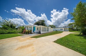 A mobile home with a paved driveway, a small garden, and a clear blue sky. - Beautiful 3-bedroom house with AC in tranquil Isabela (Isabela)