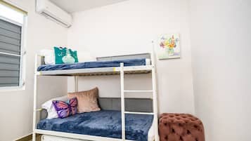 A bunk bed with a pillow, a butterfly pillow, and a small tufted ottoman.