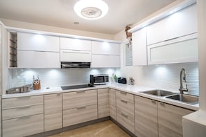 A modern kitchen with white cabinets, a microwave, a sink, and a decorative clock. - Beautiful 3-bedroom house with AC in tranquil Isabela (Isabela)