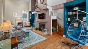 Una sala de estar moderna con chimenea, una silla colgante y una estantería.