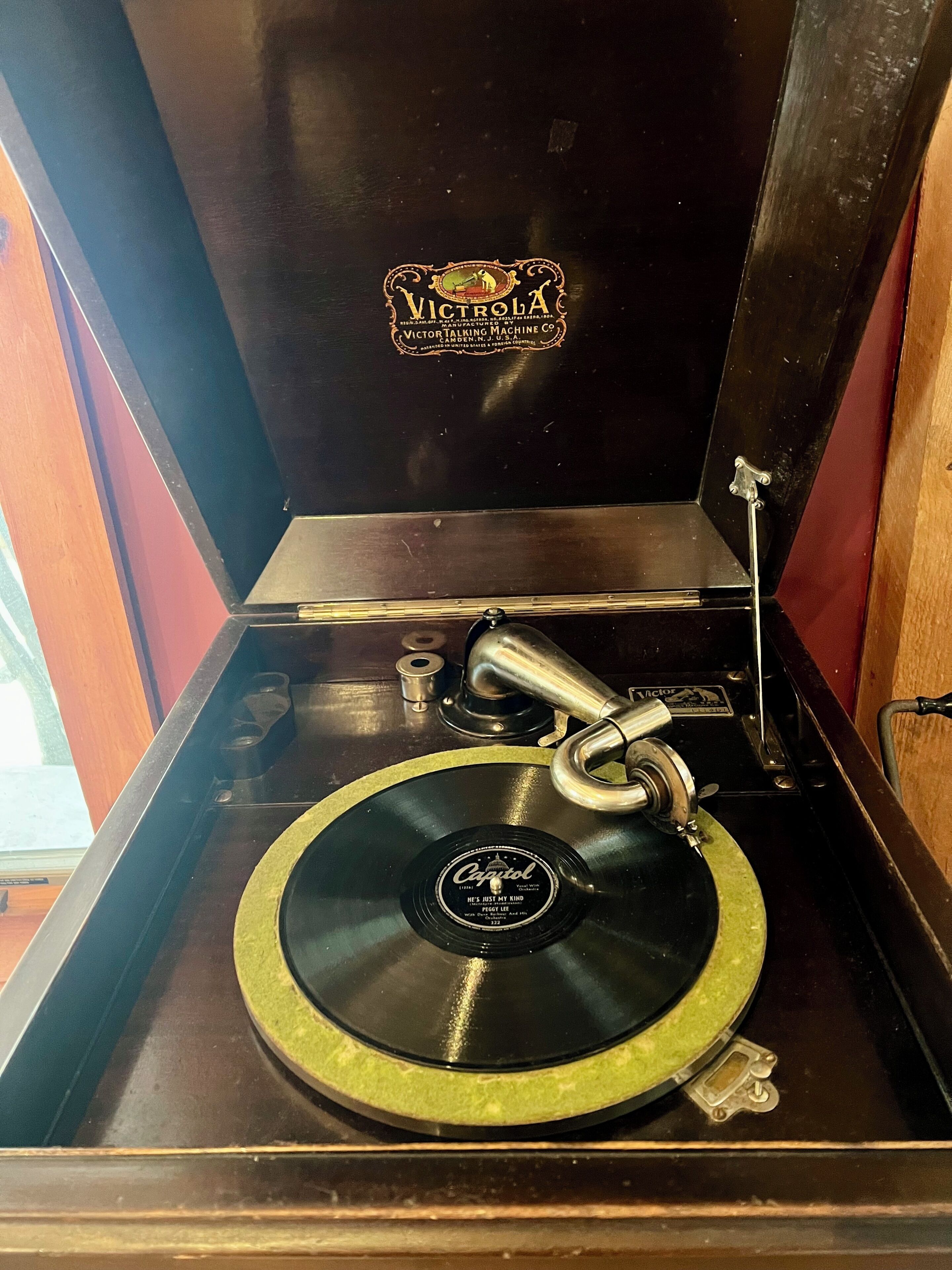 Un fonógrafo Victrola antiguo con un reproductor de discos, un brazo metálico y un disco con la etiqueta 'Capitol'.