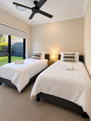 A hotel room with two beds, a ceiling fan, and a sliding glass door leading to a backyard. - STONE -  Luxury * Bay Views * Walk to Marina & Town (Nelson Bay)