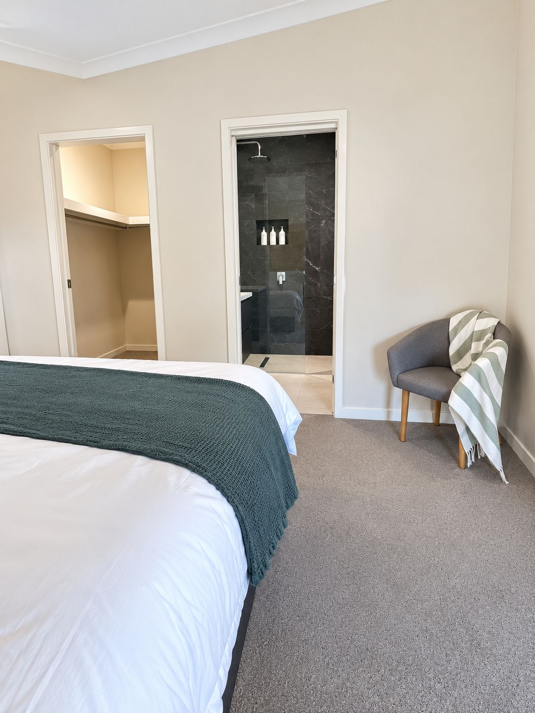 Een hotelkamer met een groot bed, een zithoek met een fauteuil en een douche.