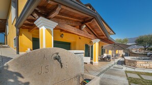 A stone bench with 'J.S.' engraved, a stone planter, and a patio area with outdoor seating. - Villa Montegolo, Happy Apartment (Costermano)