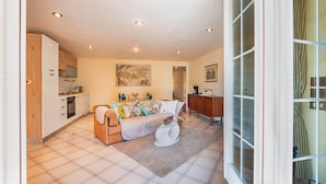 A modern living room with a sofa, coffee table, and a kitchen in the background. - Villa Montegolo, Happy Apartment (Costermano)
