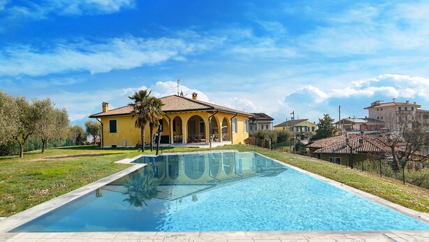 A swimming pool with a house in the background. - Villa Montegolo, Happy Apartment (Costermano)