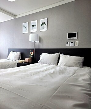A hotel room with a large bed, bedside tables, a lamp, and framed artwork on the wall. - Someone Hotel (Yeosu)