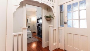A hallway with a white door, a hanging plant, and a staircase. - KozyGuru | St Peters | Peaceful Duplex Getaway (Saint Peters)
