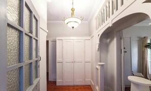 A hallway with a white door, a chandelier, and a mirror. - KozyGuru | St Peters | Peaceful Duplex Getaway (Saint Peters)