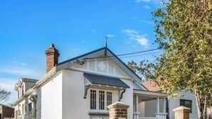 A single-story house with a gabled roof, a chimney, and a front porch. - KozyGuru | St Peters | Peaceful Duplex Getaway (Saint Peters)