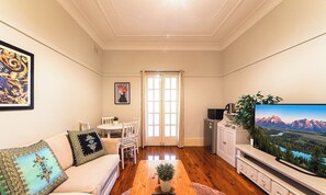A living room with a sofa, coffee table, TV, and a dining area with chairs and a table.