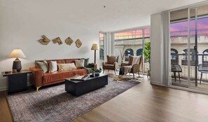 Uma sala de estar com sofá, poltronas, mesa de centro e uma janela grande com vista para uma ponte.