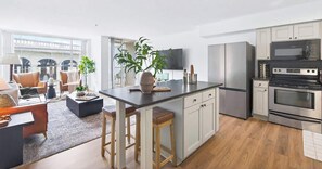 Cozinha moderna com ilha central, eletrodomésticos de aço inoxidável e vista para o exterior.