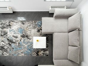 Una sala de estar moderna con un sofá gris, un tapete estampado y dos radiadores blancos.