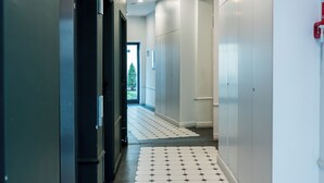 Un passadís amb un terra emblamat, parets blanques i portes que donen a habitacions.