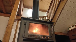 A wood-burning stove with a visible fire, a chimney, and a metal grate. - Wodinstead - A cosy large home in Bundanoon (Bundanoon)