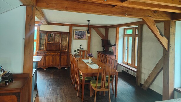 A dining area with wooden furniture, a chandelier, and a large window. - Wodinstead - A cosy large home in Bundanoon (Bundanoon)