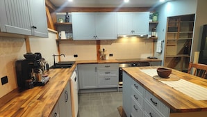 A kitchen with wooden countertops, grey cabinets, a coffee machine, and a central island. - Wodinstead - A cosy large home in Bundanoon (Bundanoon)