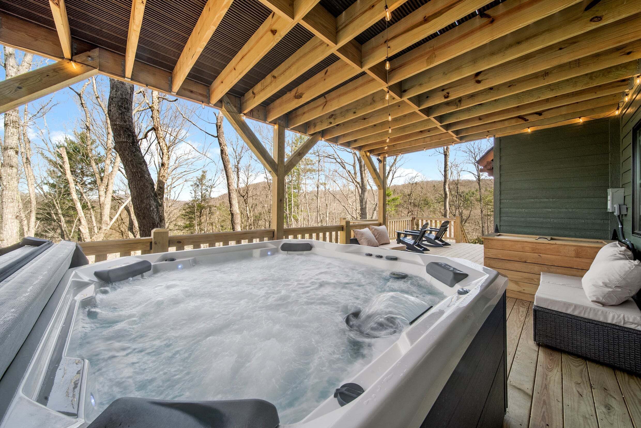 Ein Whirlpool unter einer Holzterrasse mit Blick auf Bäume und Berge.