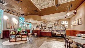 Interior de café com balcão, área de estar e diversos itens expostos em prateleiras.